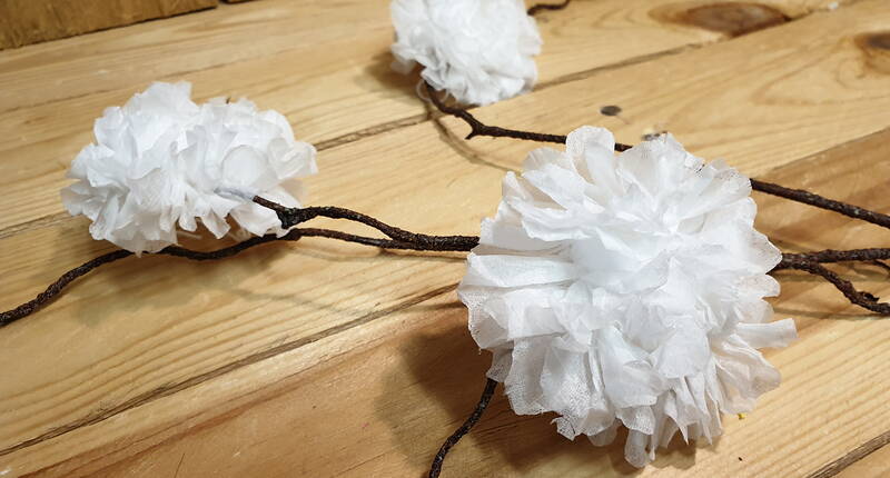 Diese fantastischen Blumen kannst du zu Hause ohne grossen Aufwand nachbasteln. Alles was du dafür benötigst, ist eine Serviette, eine Schere und ein Stück Baumwollgarn.