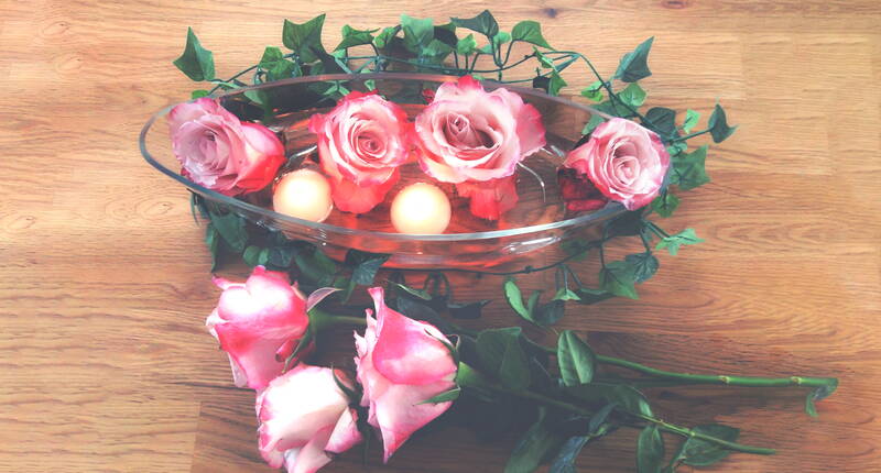 Alles, was du dazu brauchst, ist eine flache Glasschale, ein paar Rosenblüten, Schwimmkerzen und Efeu für die Dekoration.