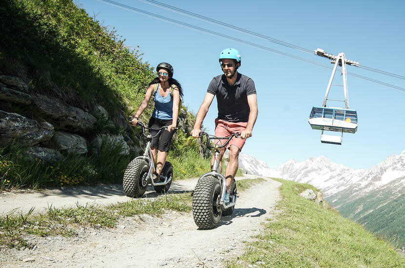 Zoom: Prendete il vostro scooter gigante alla stazione a monte della funivia Wiler-Lauchernalp e partite! Come coronamento della vostra escursione o semplicemente per divertimento, sfrecciate lungo la strada ben tenuta fino a Wiler.