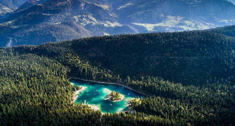 Familienausflug Caumasee – Der Caumasee ist auf drei Seiten von Wald umgeben; in der Mitte des Sees liegt eine bewaldete Insel. Das Wasser ist auffallend türkisgrün und angenehm kühl.